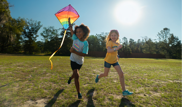 Girl flying a kite and running with another girl