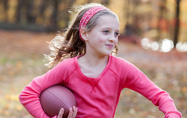 young girl scout running with football