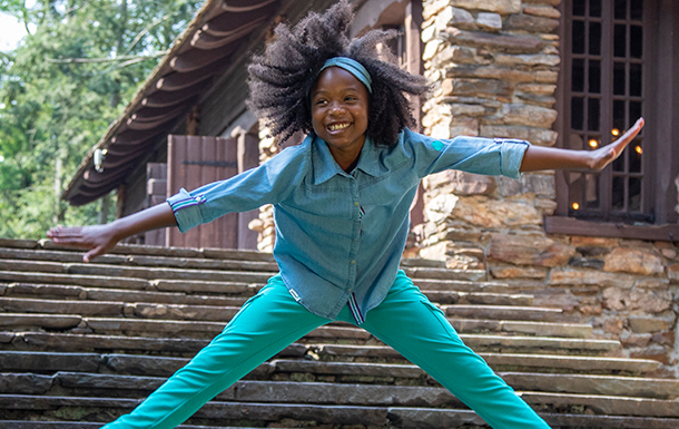 girl scout jumping in front of stone building