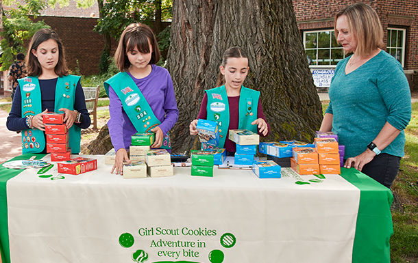group of junior girl scouts at cookie booth with volunteer