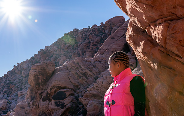 teen girl scout hiking on cliff pointing looking at sun