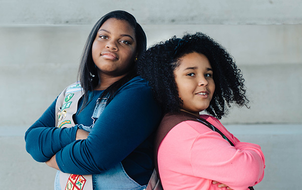 ambassador girl scout crossing arms standing back-to-back with brownie girl scout