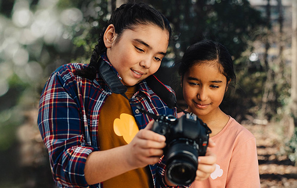 two girl scouts looking at a digital camera outside